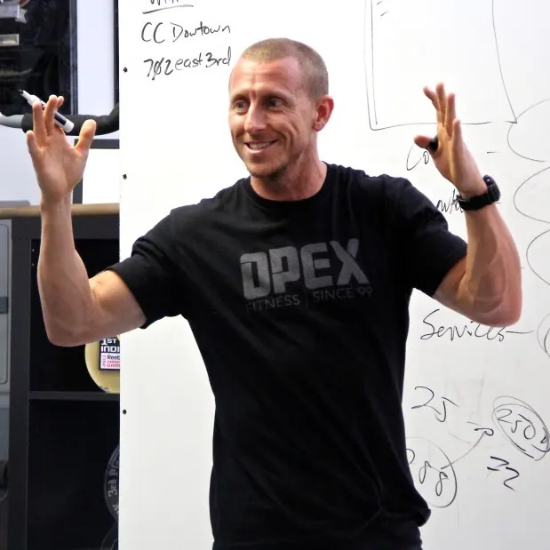 James FitzGerald teaching at a whiteboard in an OPEX shirt